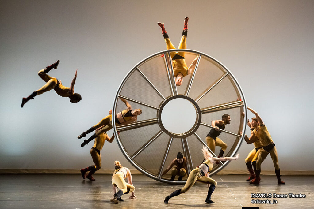 Dancers from @diavolo_la company performing mid-air on spinning wheel.