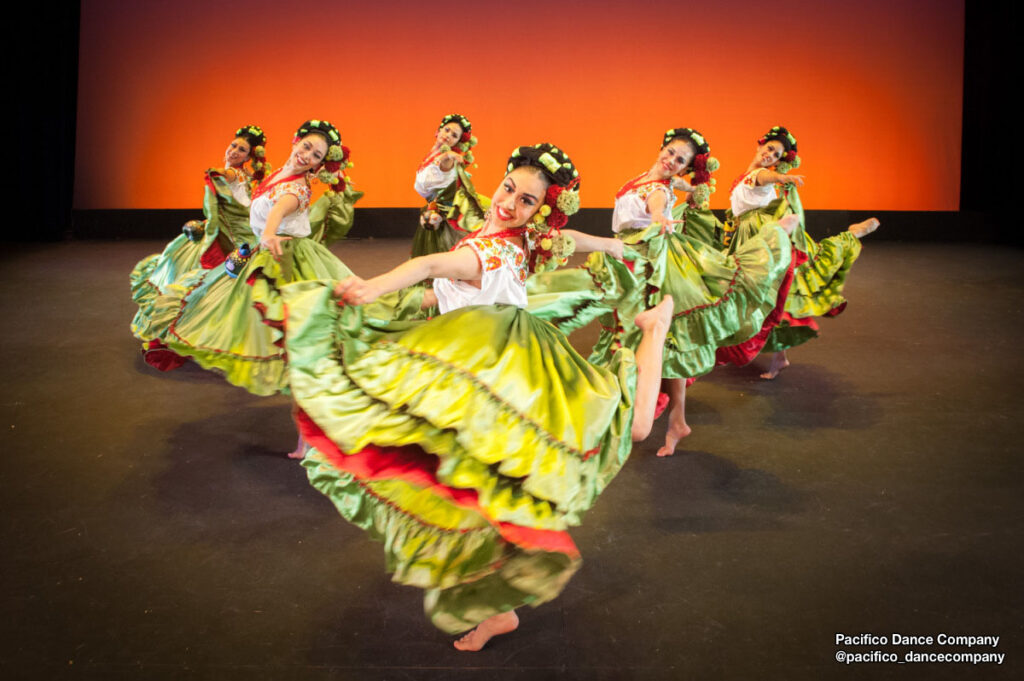 Female dancers from @pacifico_dancecompany holding bright green skirts.